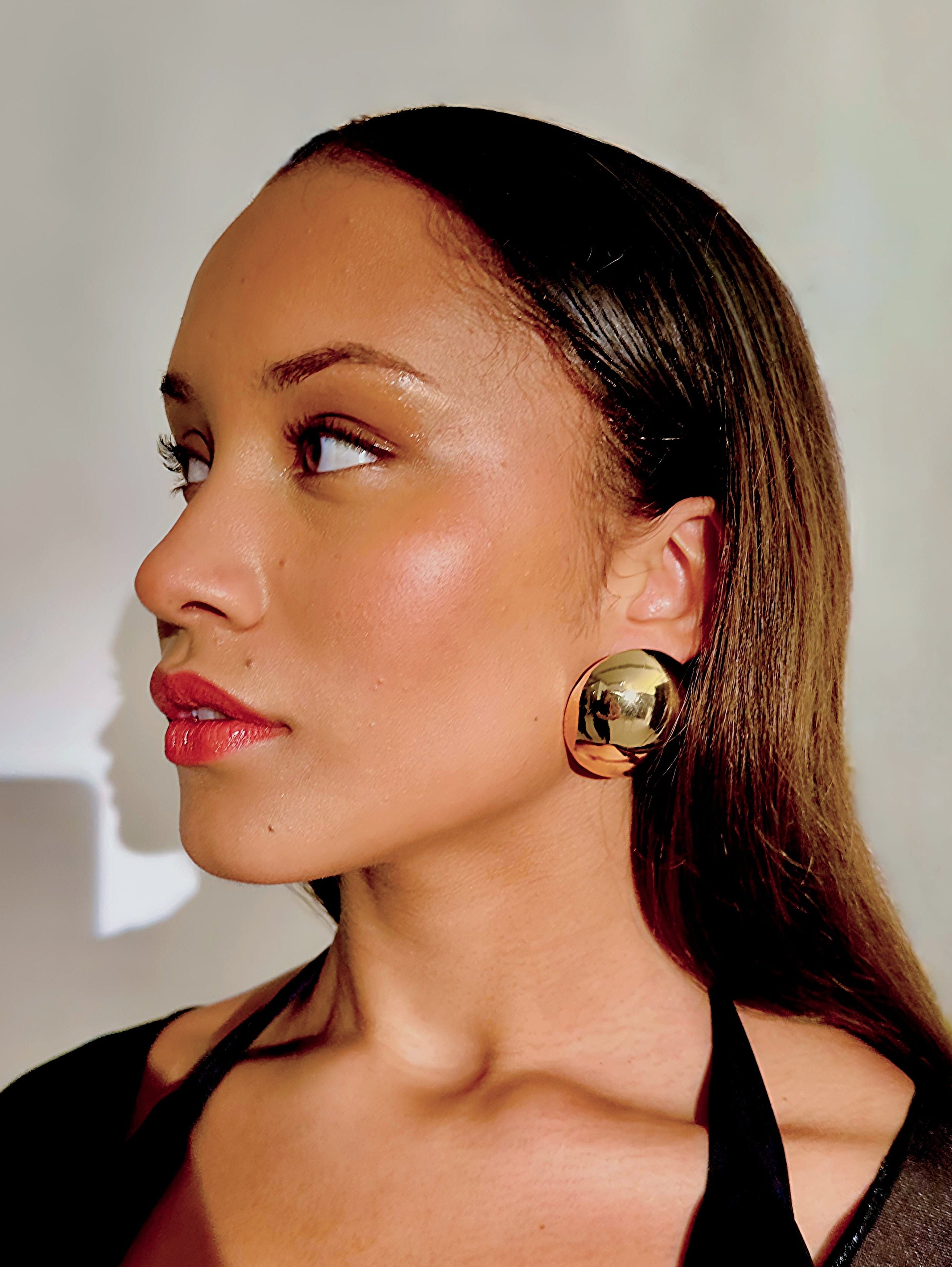 Woman wearing gold earrings with a blurred background