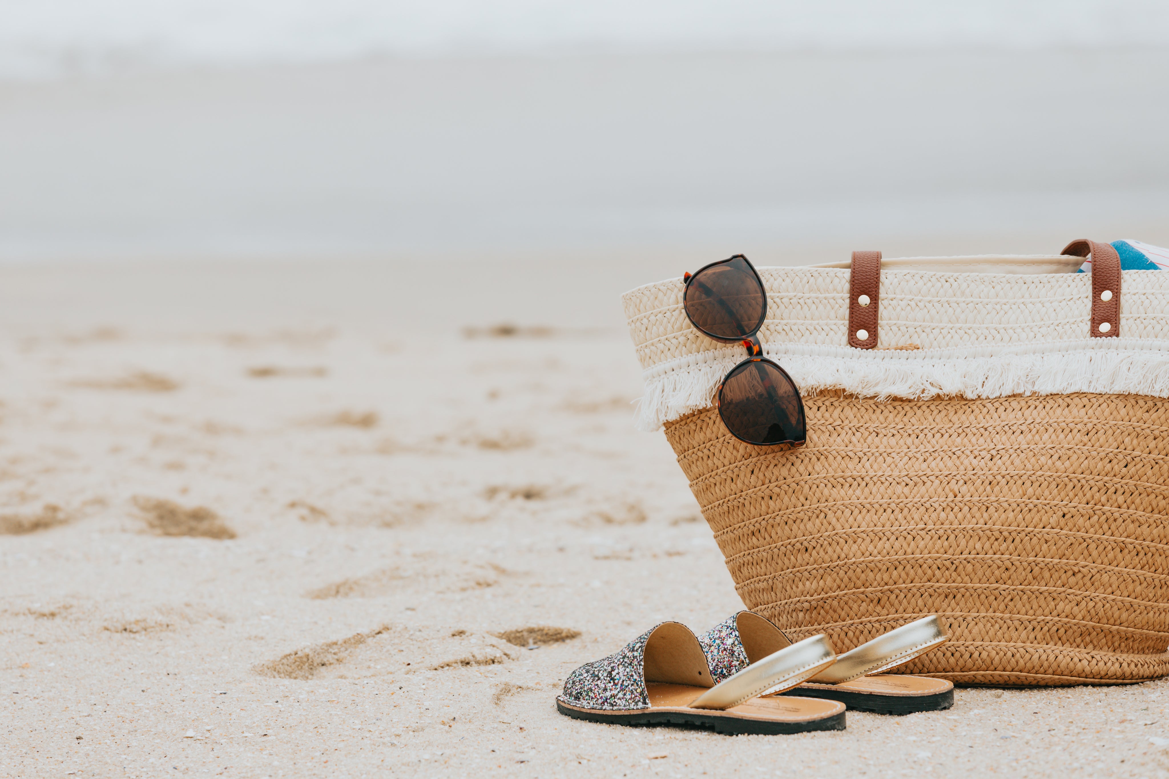 sandy-beach-with-sandals-sunglasses-and-a-beach-bag.jpg